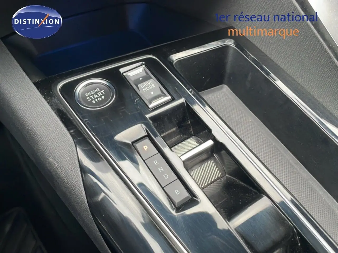 Gros plan sur la console centrale noire brillante du Peugeot 3008 hybride avec boutons start/stop et sélection mode conduite.