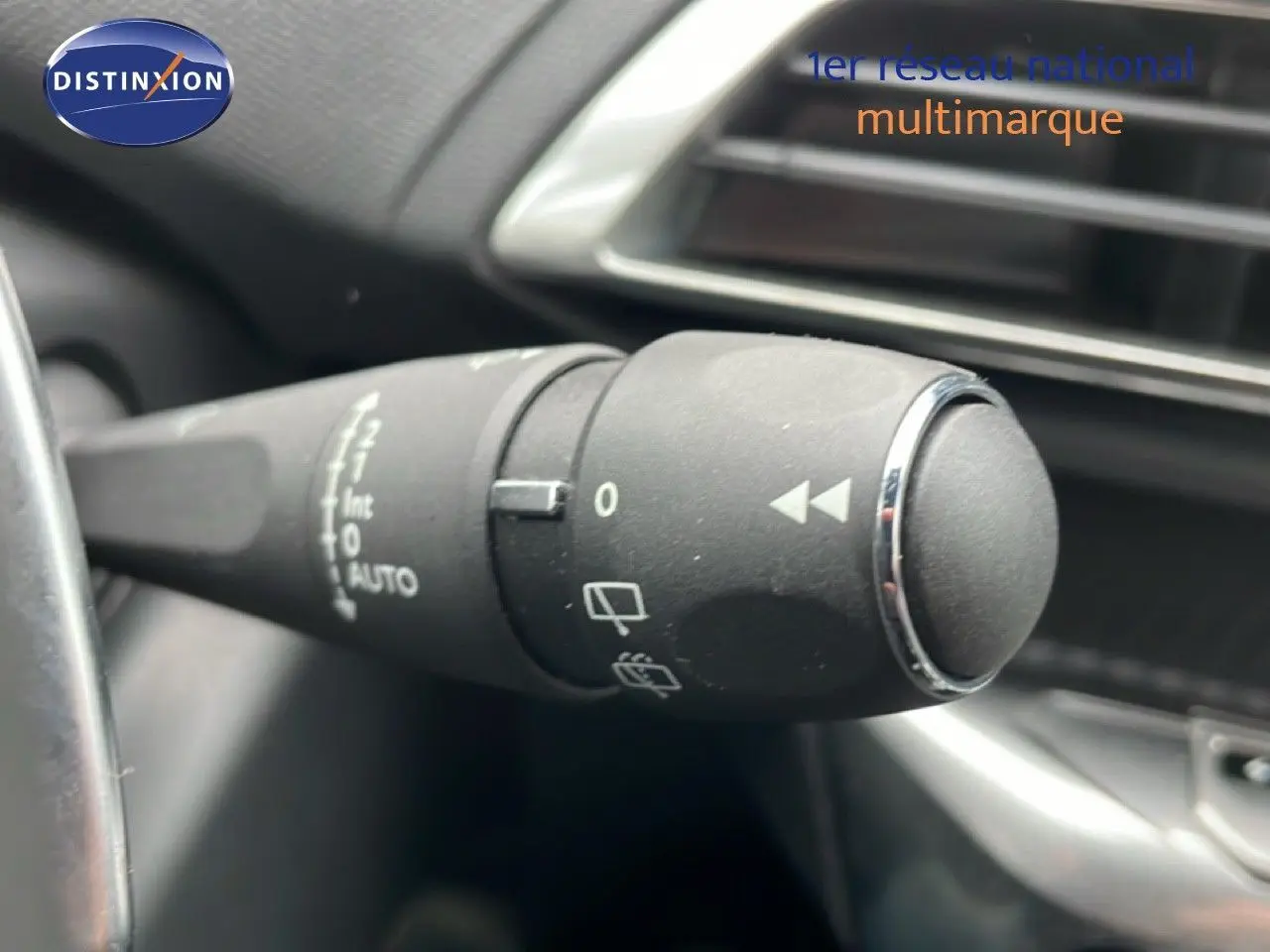 Gros plan sur la manette de commande des essuie-glaces du Peugeot 3008 hybride gris, intérieur noir visible en arrière-plan.