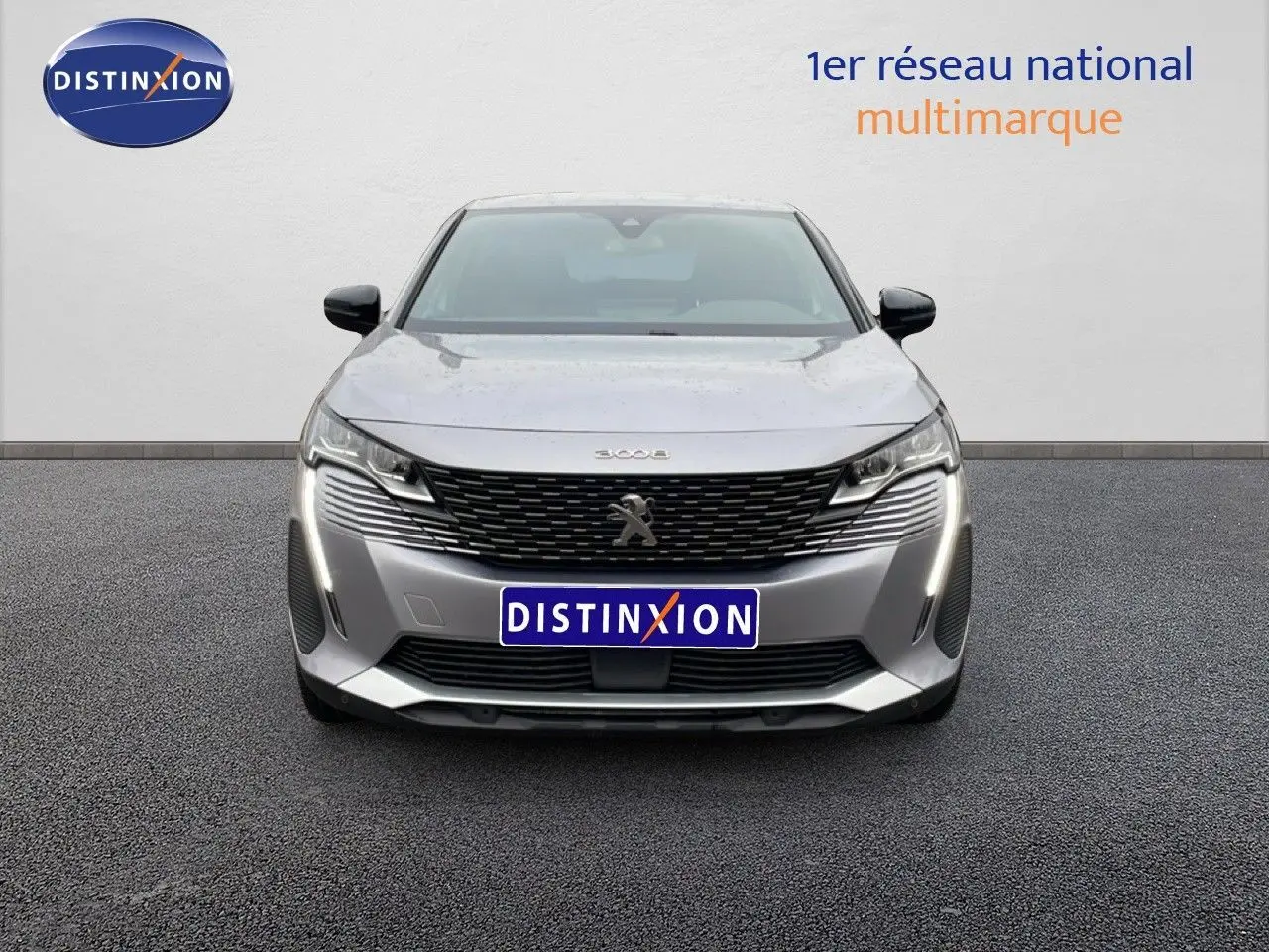 Vue frontale d’un Peugeot 3008 gris Artense métal 2024 avec calandre noire et feux LED verticaux allumés.