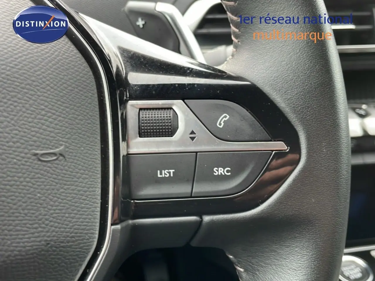 Gros plan sur les commandes gauche du volant cuir noir du Peugeot 3008 hybride rechargeable gris Artense 2024.