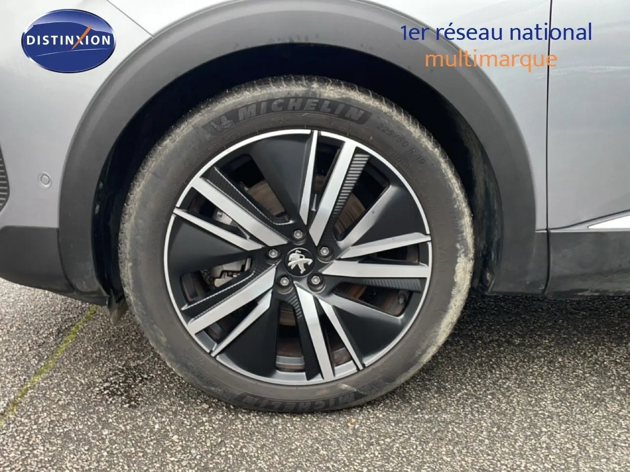 Gros plan sur la roue avant gauche d’un Peugeot 3008 gris Artense avec jante alliage bicolore 19 pouces.