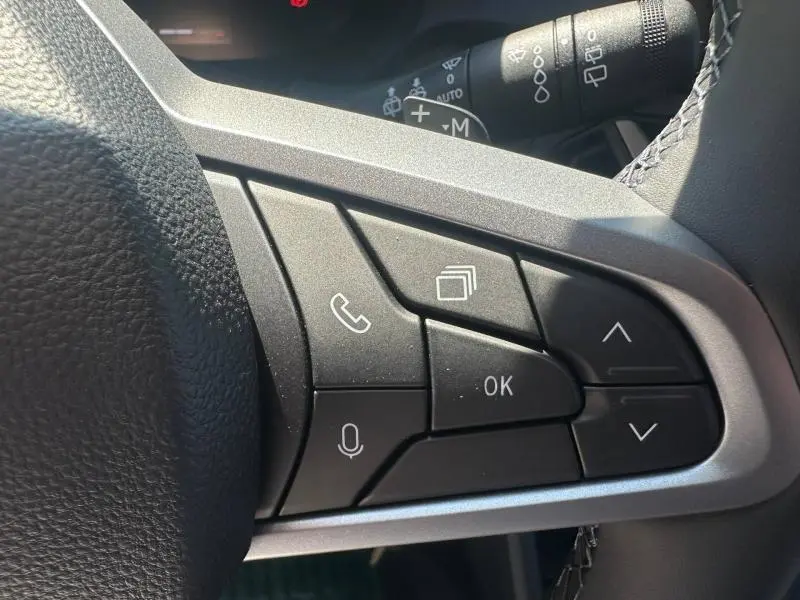 Gros plan sur les commandes multifonctions côté gauche du volant du Dacia Duster 2026, boutons noirs avec icônes blanches.