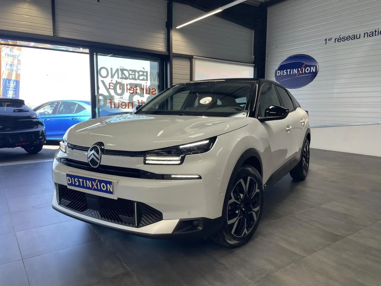 Citroën C4 blanche vue 3/4 avant droit en intérieur avec toit noir et jantes alliage noires.