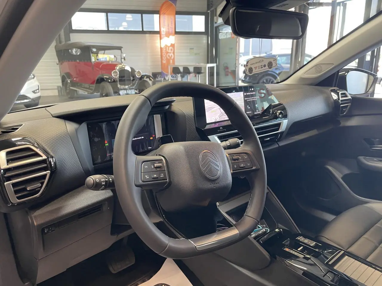 Intérieur de la Citroën C4 blanc, vue du poste de conduite avec volant cuir et écran tactile central.