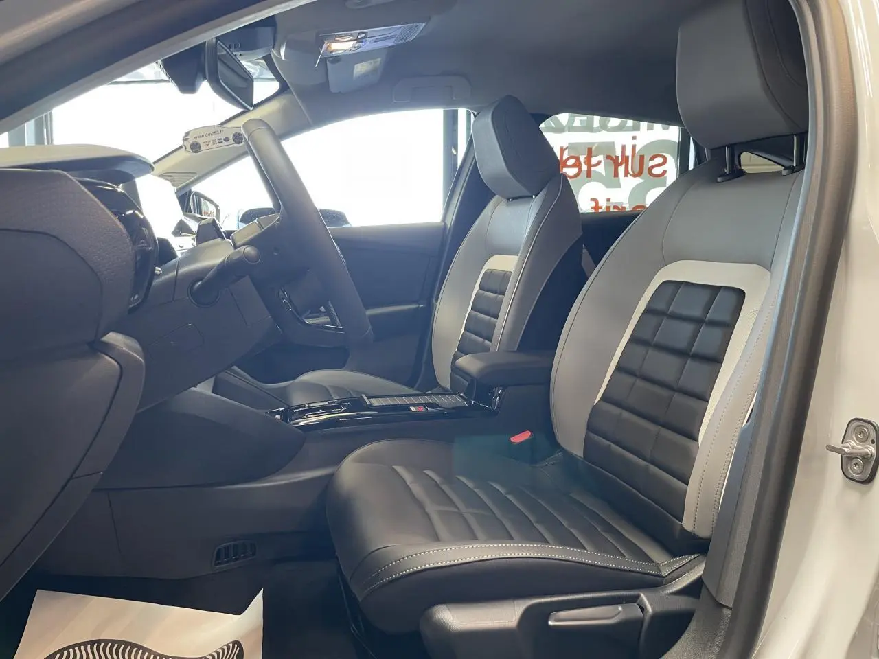 Vue intérieure côté conducteur de la Citroën C4 blanche avec sièges Advanced Comfort bicolores noir et gris clair.