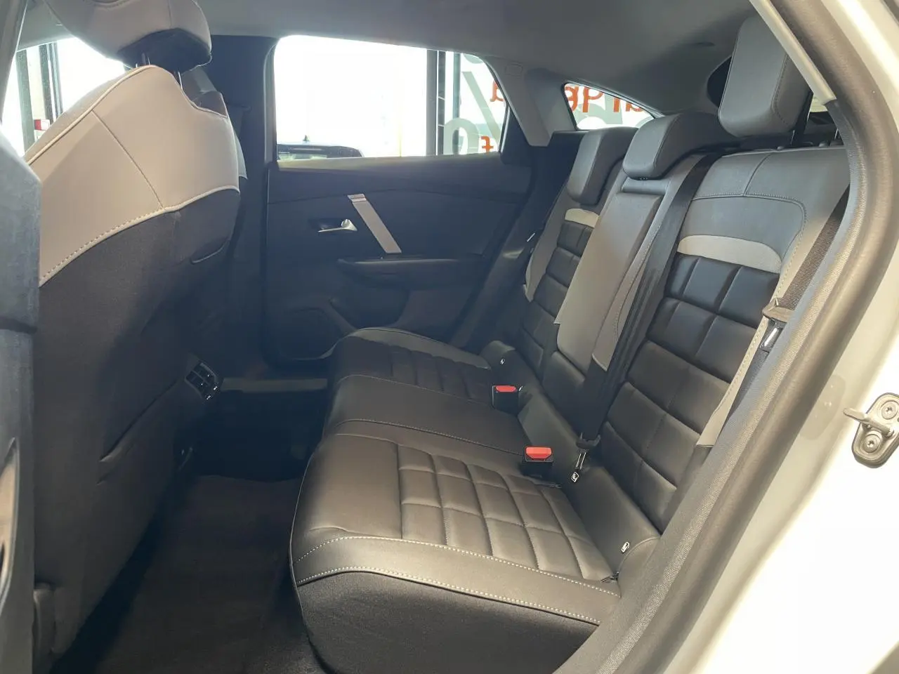 Vue côté droit de la banquette arrière noire et grise de la Citroën C4 blanche, avec portes ouvertes et habillage intérieur sombre.