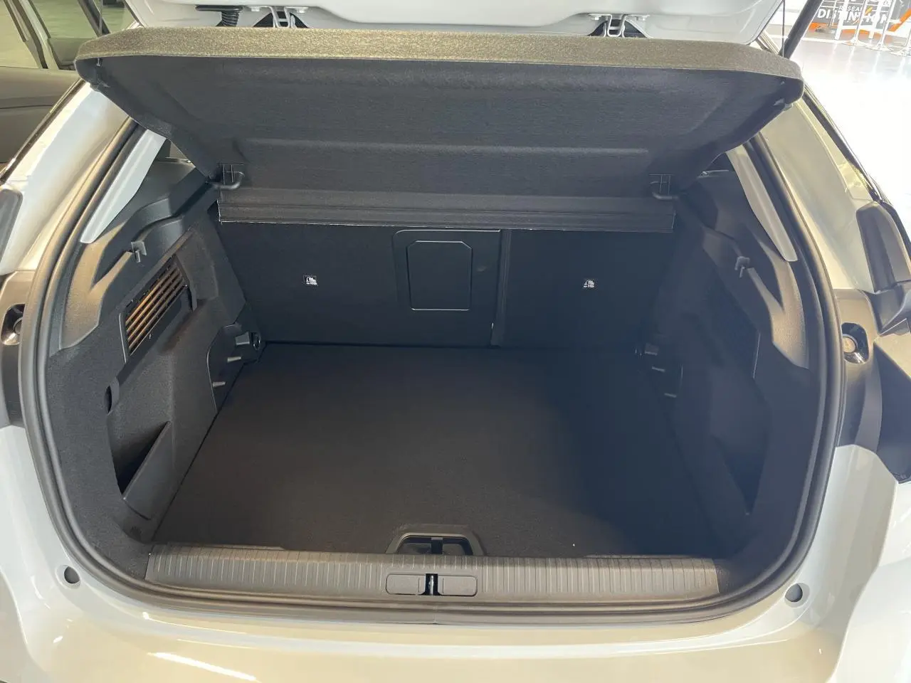 Coffre ouvert vu de l'arrière d'une Citroën C4 blanche, montrant un espace de chargement propre et spacieux.