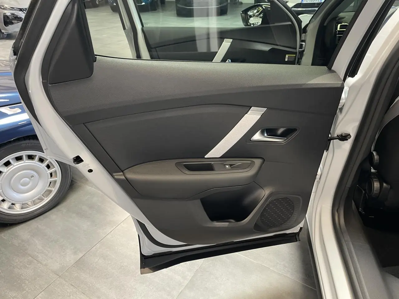 Vue intérieure sur la porte arrière gauche ouverte d'une Citroën C4 blanche, avec garniture noire et poignée argentée.