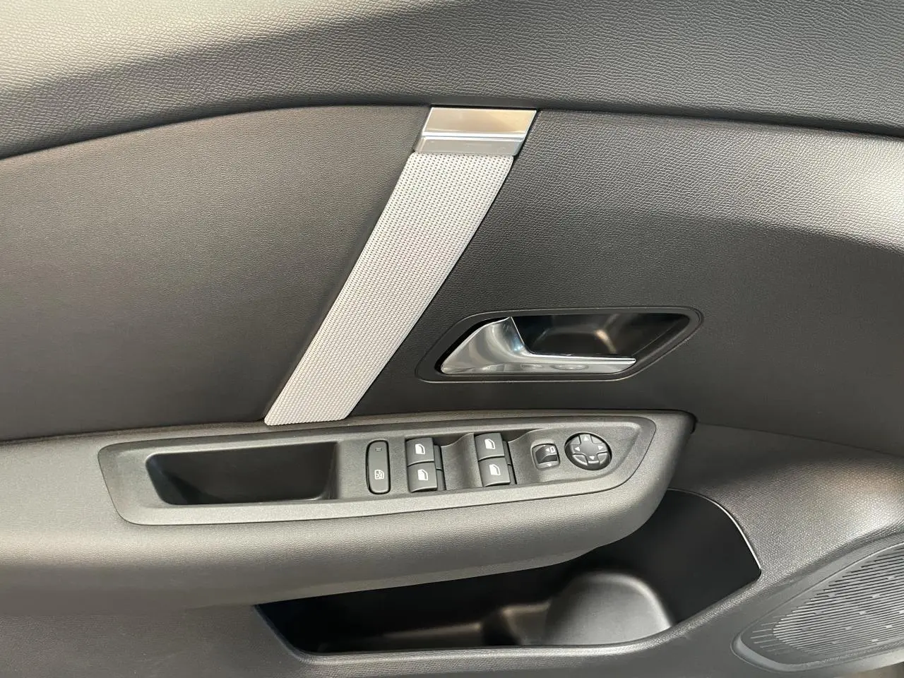 Détail de la porte avant gauche noire de la Citroën C4 avec commandes électriques et poignée argentée.