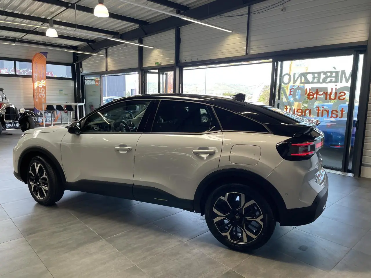 Citroën C4 blanche vue de profil côté gauche, toit noir bi-ton et jantes alliage 18 pouces en showroom.