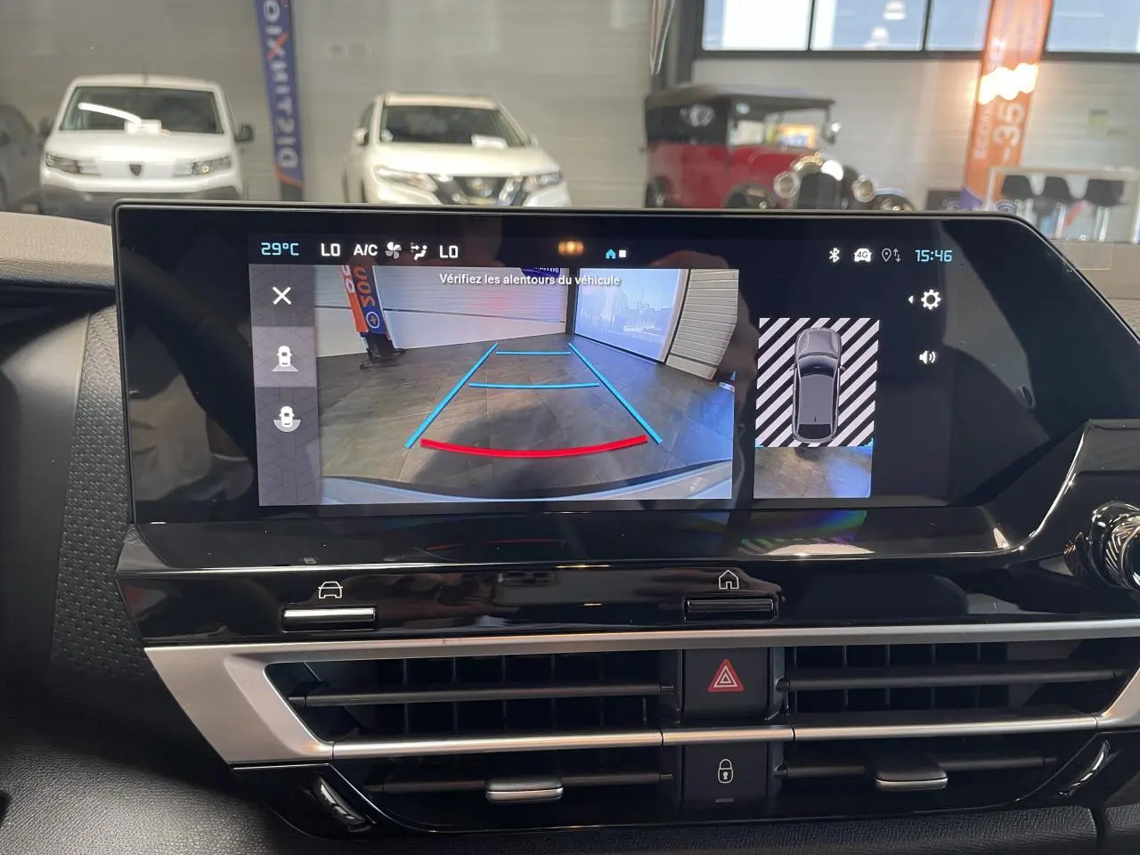 Écran central affichant la caméra de recul d'une Citroën C4 blanche en intérieur de garage.