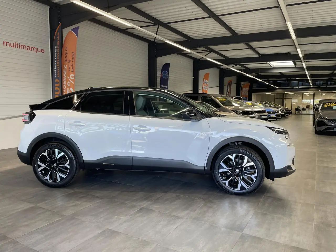Vue de profil droit d'une Citroën C4 blanche avec toit noir et jantes alliage 18 pouces en concession.