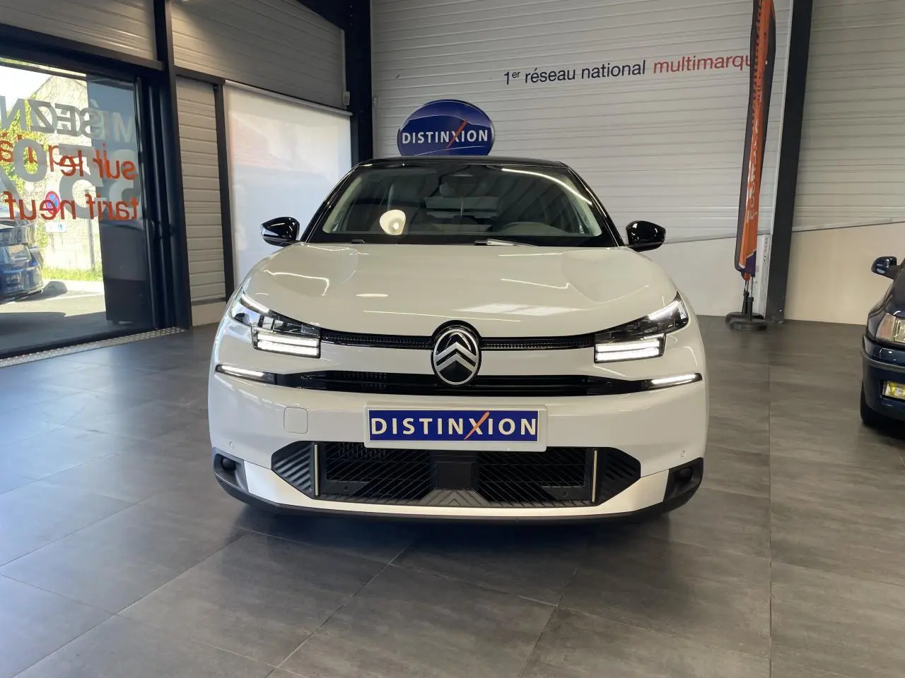 Citroën C4 blanche vue de face en intérieur, avec toit bi-ton noir et signature lumineuse LED distinctive.