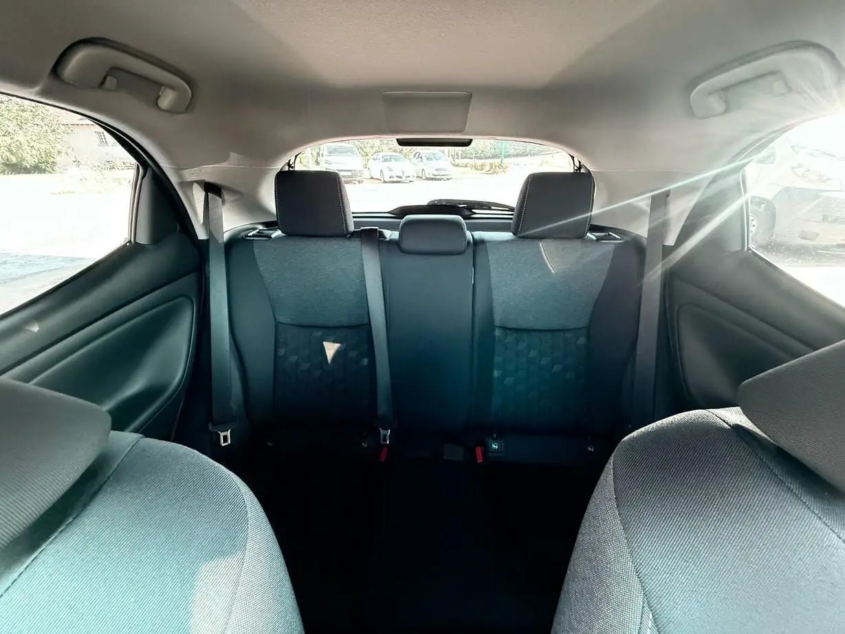 Vue intérieure arrière de la Toyota Yaris Hybrid 116ch 2025, montrant les sièges arrière en tissu gris foncé.