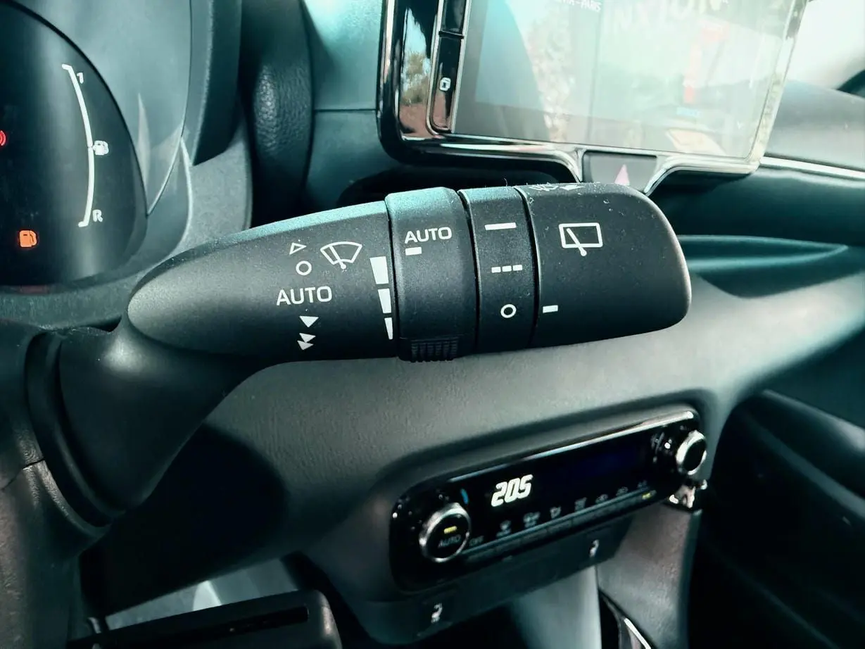 Gros plan sur la commande d'essuie-glace à gauche du volant dans l'habitacle noir de la Toyota Yaris Hybrid 2025.