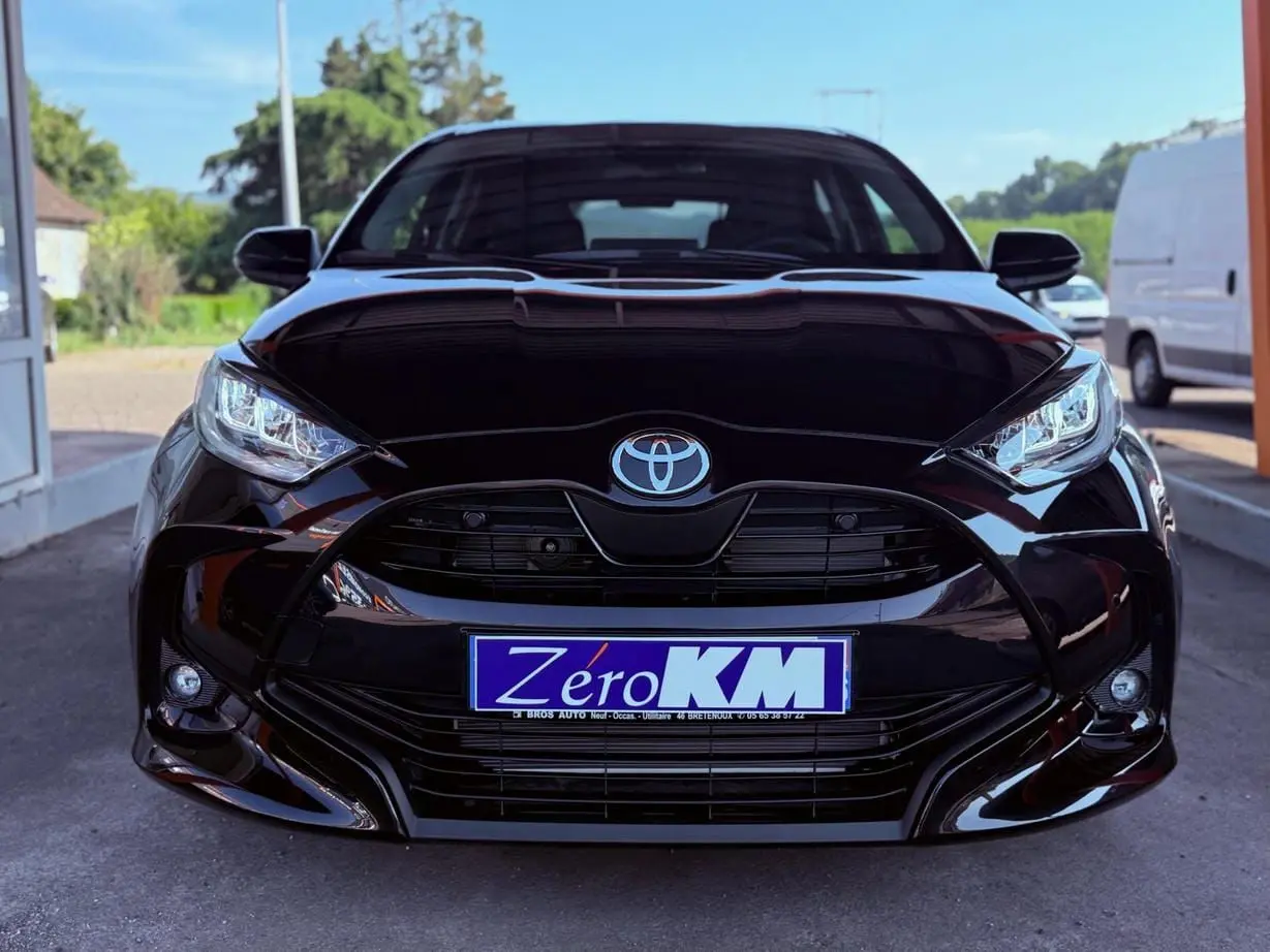 Vue frontale d'une Toyota Yaris Hybrid noire avec calandre large et phares LED distinctifs.
