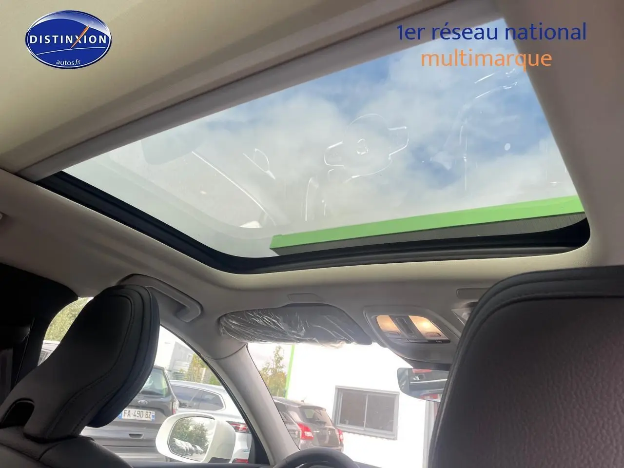 Toit panoramique en verre vu de l'intérieur avant du Volvo XC60 gris avec sièges en cuir noir.