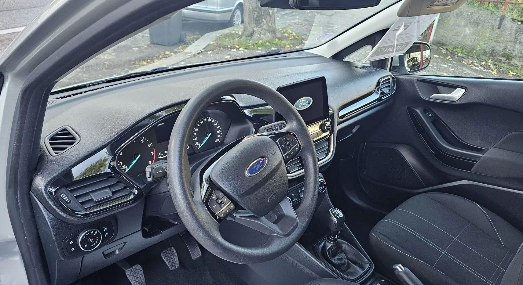 Intérieur avant gauche d'une Ford Fiesta 2021 gris lunaire, volant multifonction et tableau de bord avec écran tactile.