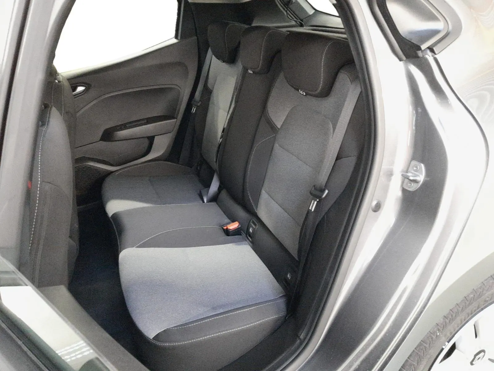Vue intérieure arrière côté droit de la Renault Clio V E-Tech gris schiste, montrant la banquette arrière en tissu gris à motifs.