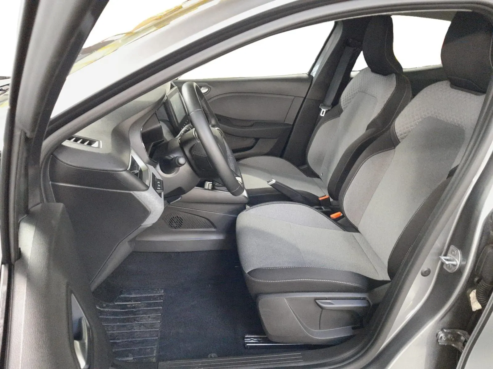 Vue intérieure côté conducteur de la Renault Clio V E-Tech gris schiste, avec sellerie textile gris à motif 3D.