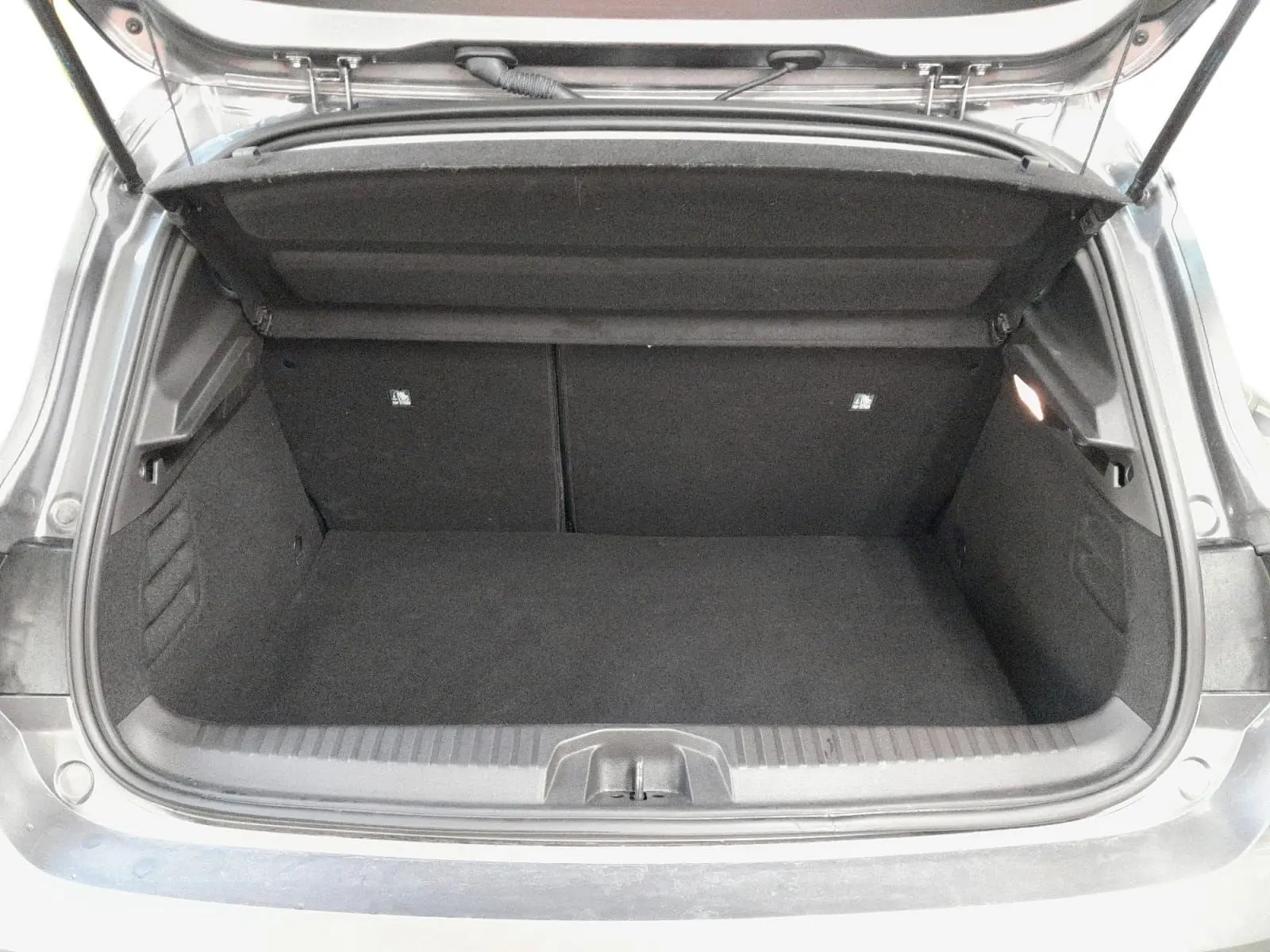 Coffre ouvert d'une Renault Clio V gris schiste, vue arrière montrant l'espace de chargement vide et la trappe de roue de secours.