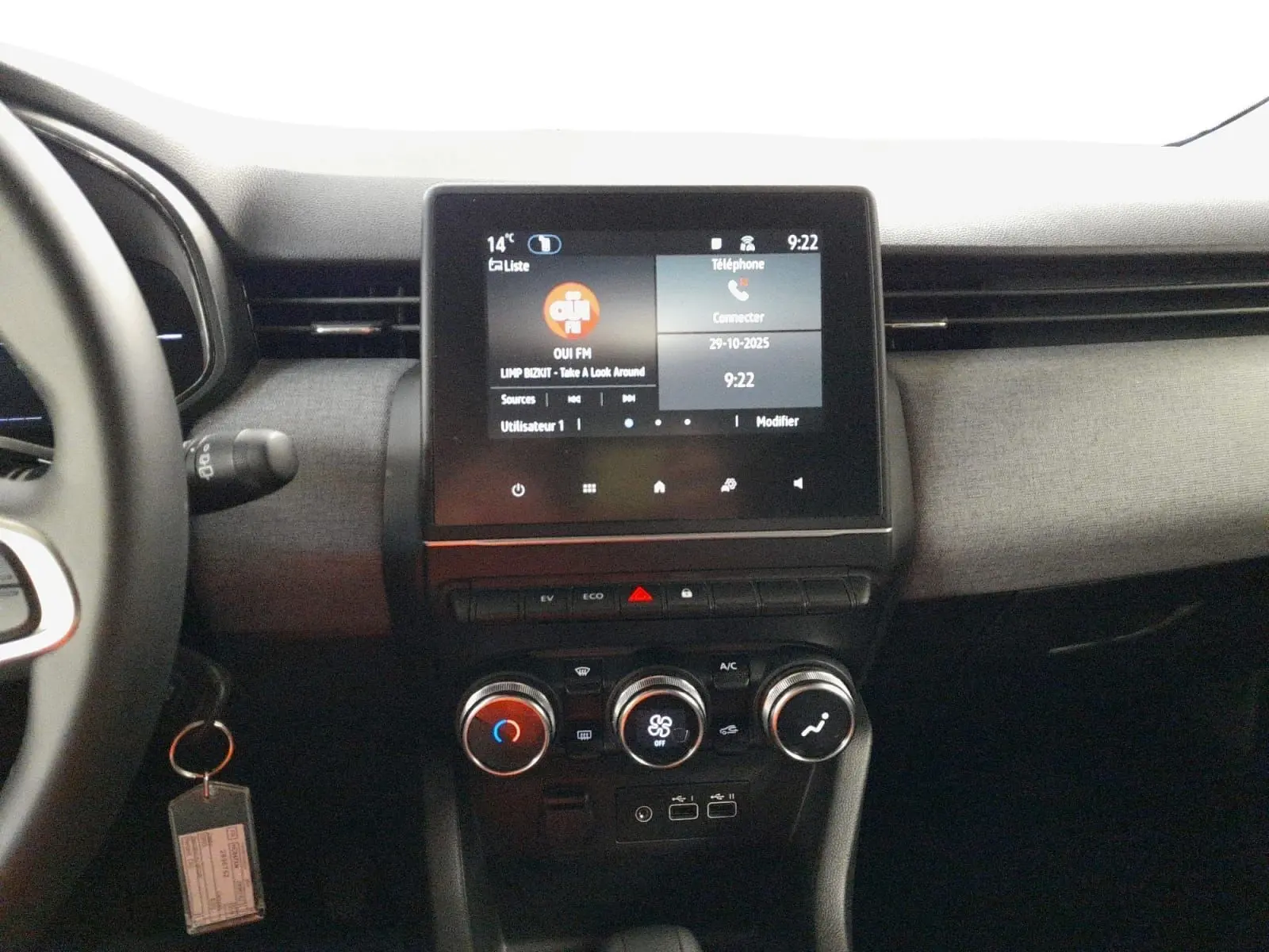 Vue intérieure centrée sur la console centrale de la Renault Clio V E-Tech avec écran tactile et commandes climatisation.