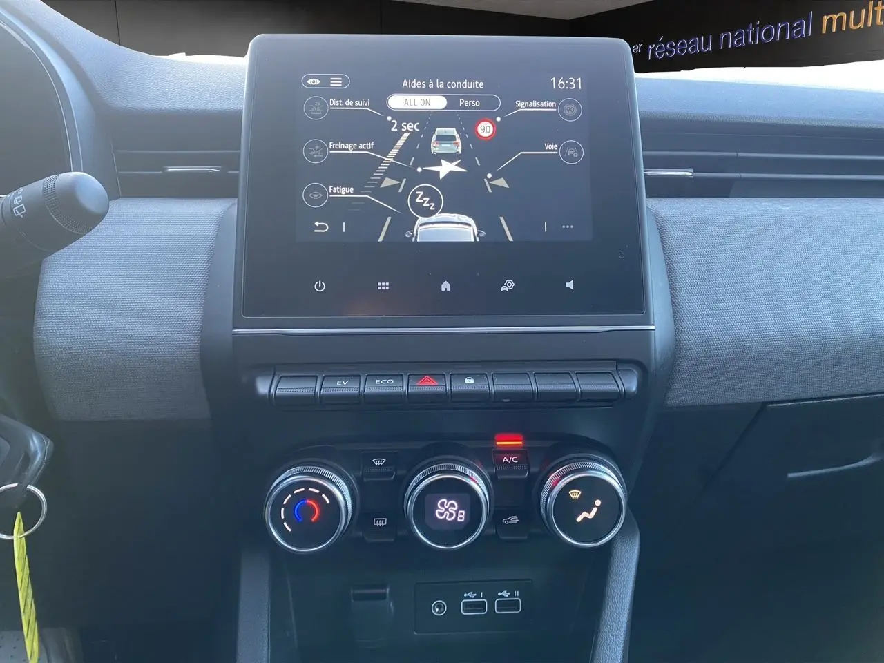 Vue intérieure du tableau de bord de la Renault Clio V E-Tech gris schiste, avec écran tactile et commandes climatisation.