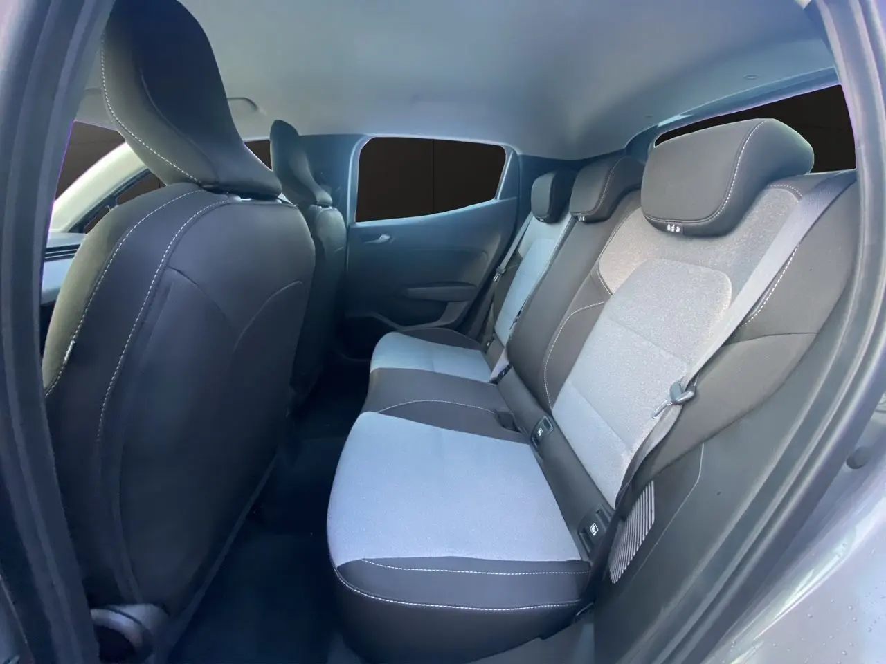 Vue intérieure arrière droite de la Renault Clio V E-Tech gris schiste, montrant la banquette arrière en tissu gris et noir.