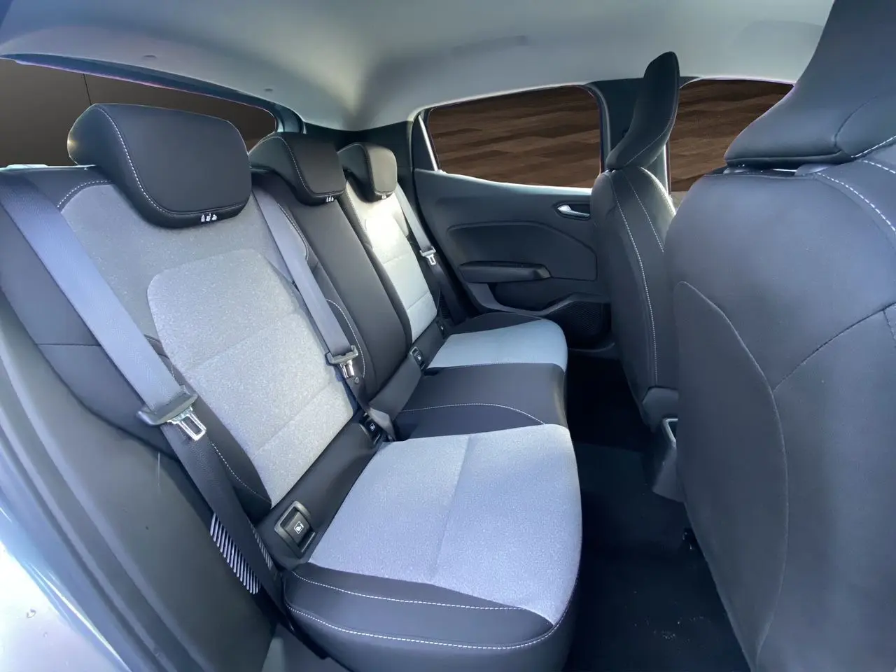 Vue intérieure arrière droite de la Renault Clio V E-Tech gris schiste, montrant les sièges arrière en tissu gris et noir avec ceintures de sécurité.