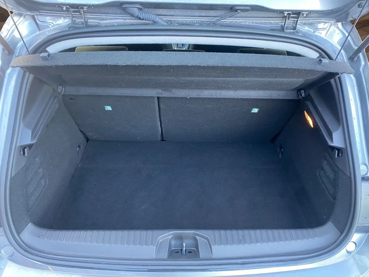 Coffre ouvert vu de l'arrière d'une Renault Clio V gris schiste, montrant un espace de chargement vide et propre.