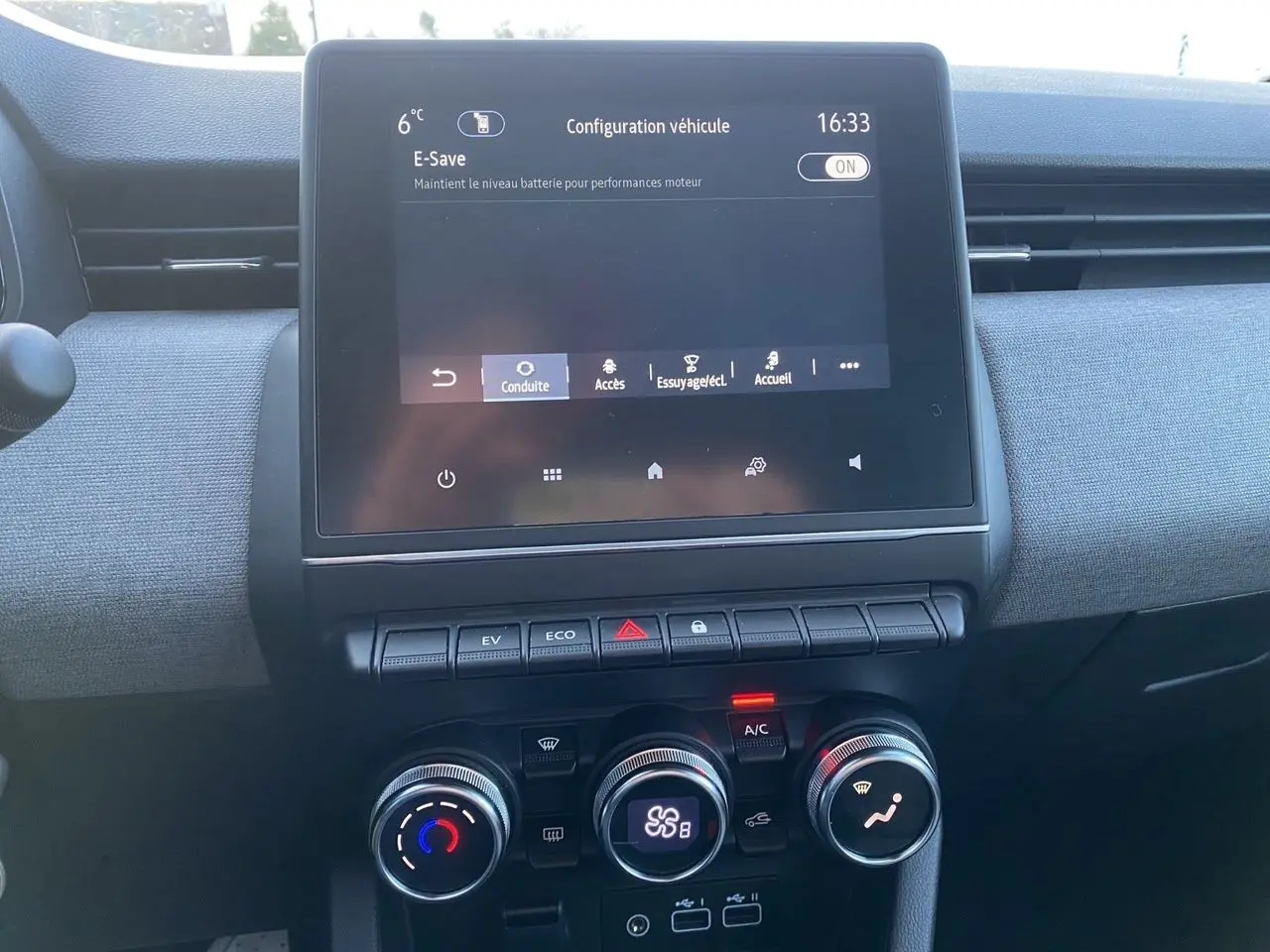Vue intérieure centrée sur l’écran tactile et les commandes de climatisation d’une Renault Clio V gris schiste.