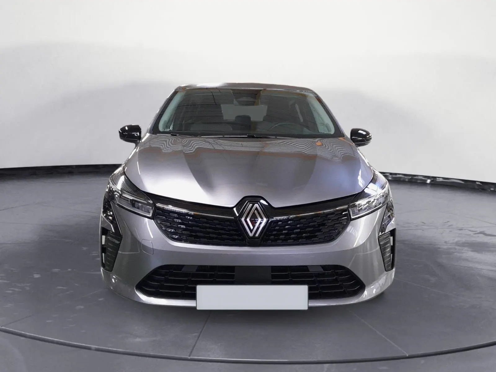 Vue avant d'une Renault Clio V E-Tech Full Hybrid 145 gris schiste avec calandre noire et phares LED allumés.