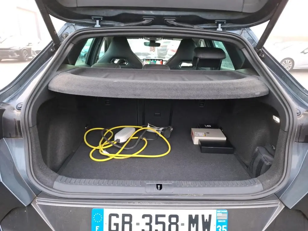 Vue arrière du coffre ouvert d'une CUPRA Formentor gris, avec câble de recharge jaune visible à l'intérieur.