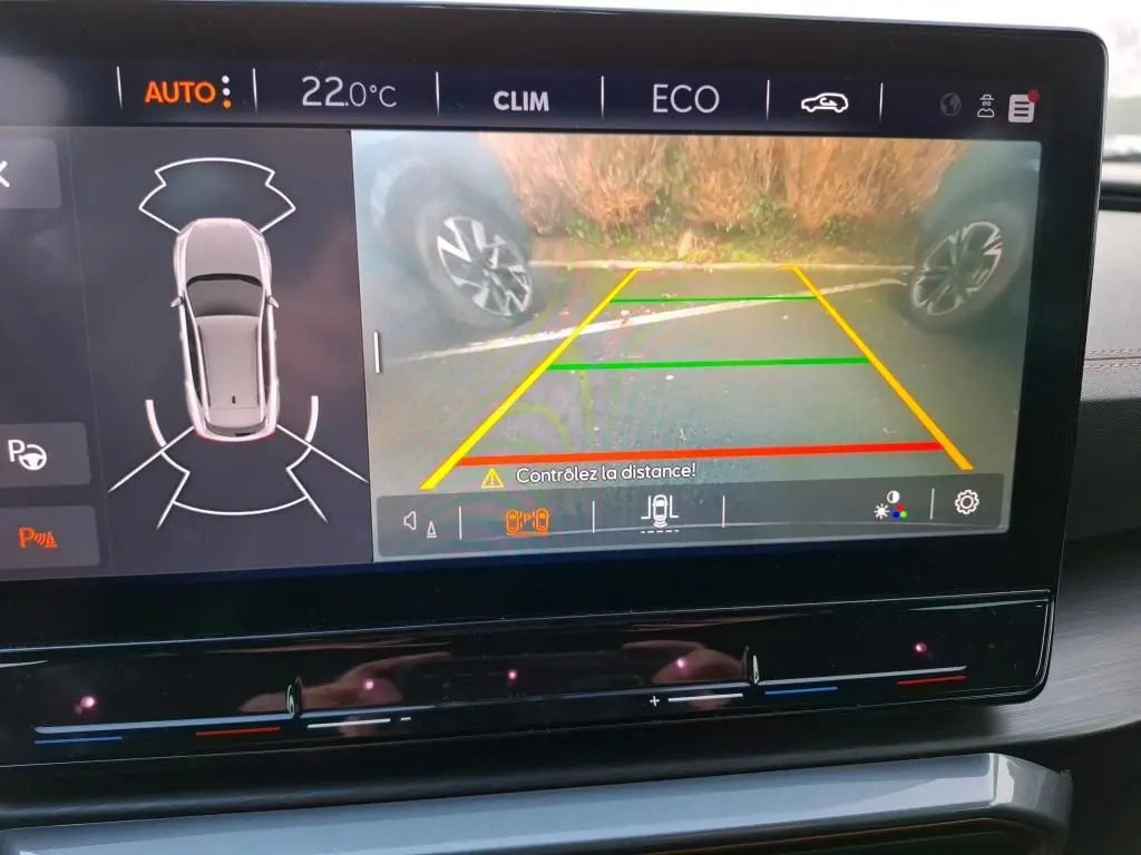 Écran tactile intérieur montrant la caméra de recul et l’aide au stationnement du CUPRA Formentor gris, vue du tableau de bord.
