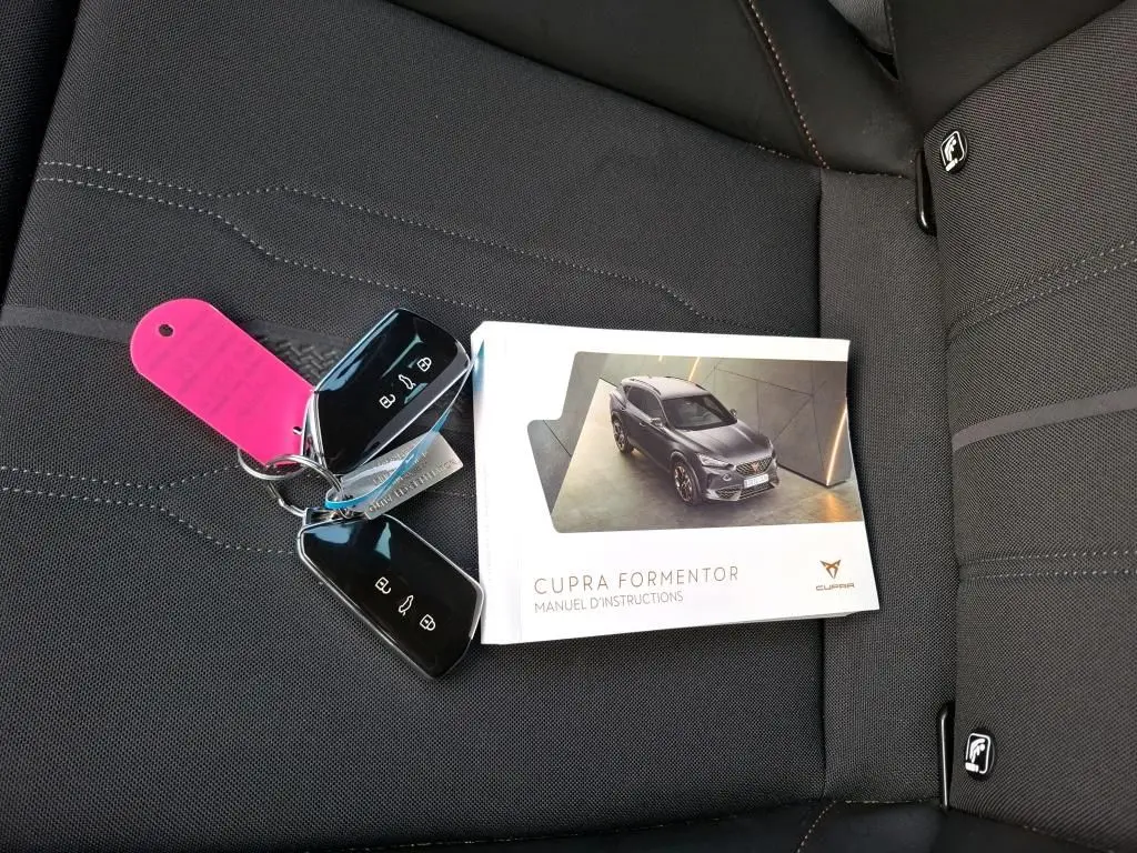 Manuel d'instructions avec photo du CUPRA Formentor gris en 3/4 avant et deux clés sur siège textile noir.