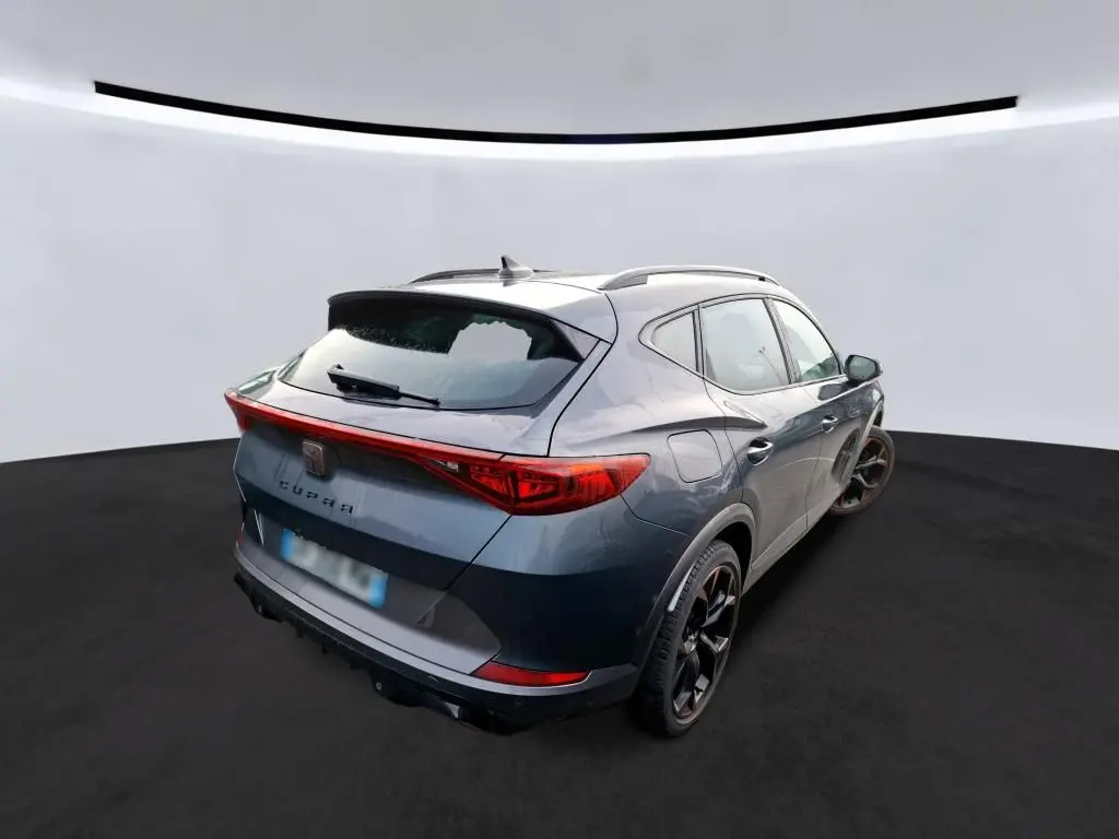 Vue 3/4 arrière droite du CUPRA Formentor gris avec jantes noires et bandeau lumineux arrière à LED.