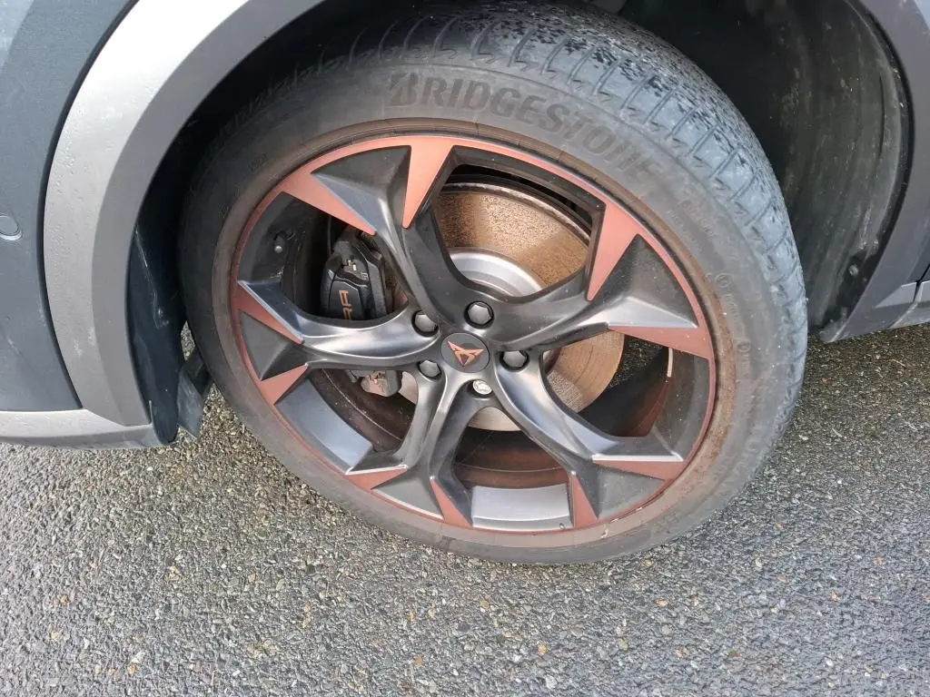 Gros plan sur la jante alliage 19 pouces bicolore noir et copper du côté avant droit du CUPRA Formentor gris.