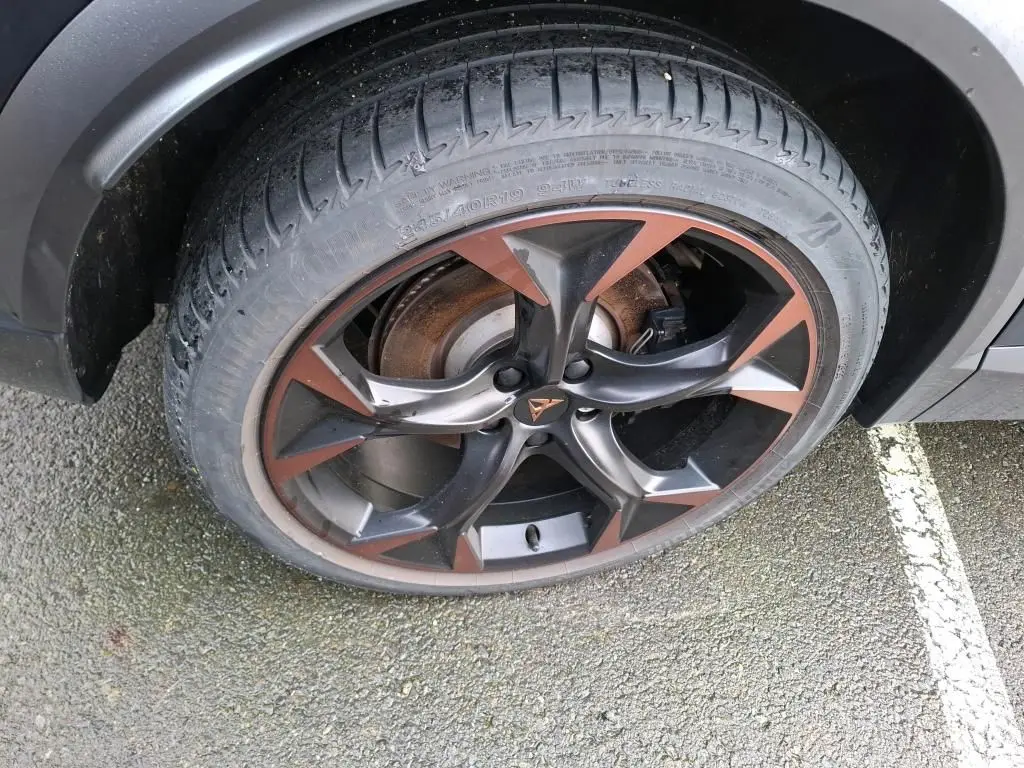 Gros plan sur la jante alliage 19 pouces bicolore noir et copper du côté avant droit du CUPRA Formentor gris.