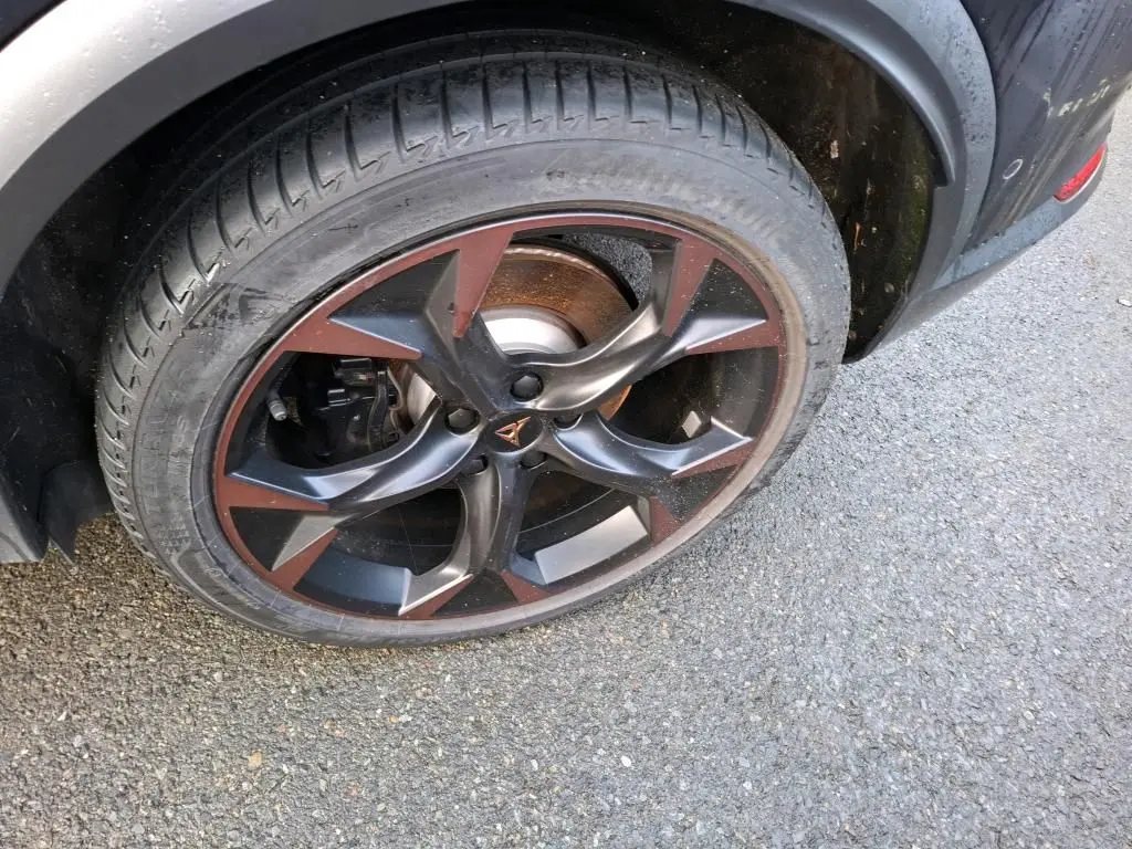 Gros plan sur la jante 19 pouces bicolore noir et cuivre du côté arrière droit du CUPRA Formentor gris.