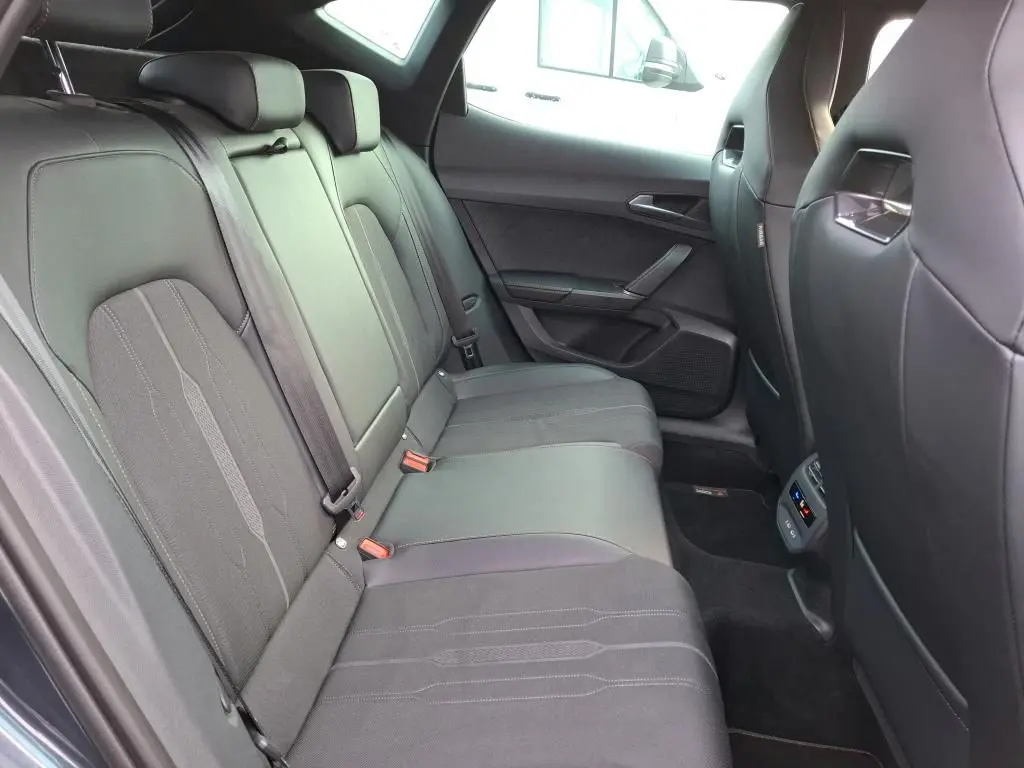 Vue intérieure côté droit des sièges arrière noirs en textile du CUPRA Formentor gris avec surpiqûres et ceintures de sécurité.