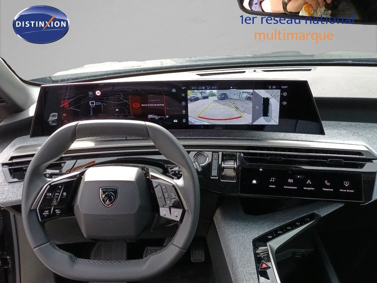 Vue intérieure frontale du tableau de bord et volant gris noir du Peugeot 5008 2025 avec écran numérique large et caméra de recul affichée.