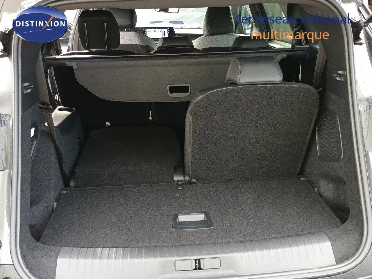 Vue arrière du coffre ouvert du Peugeot 5008 gris titane, montrant la banquette arrière partiellement rabattue.