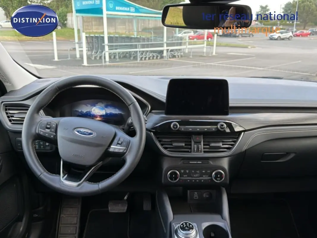 Vue intérieure avant du Ford Kuga 2024 noir, montrant le volant multifonction, écran tactile central et tableau de bord moderne.