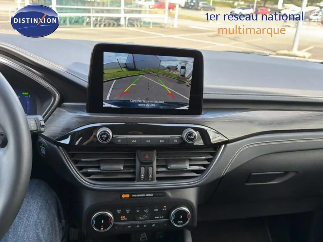 Vue intérieure du tableau de bord du Ford Kuga 2024 noir, avec écran tactile affichant la caméra de recul.