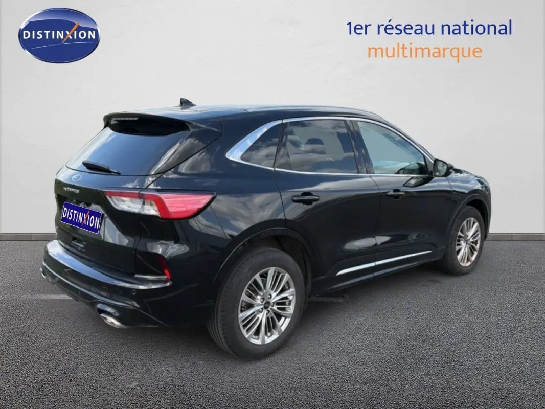 Vue 3/4 arrière droite d'un Ford Kuga noir 2024 avec jantes alliage et barres de toit visibles.