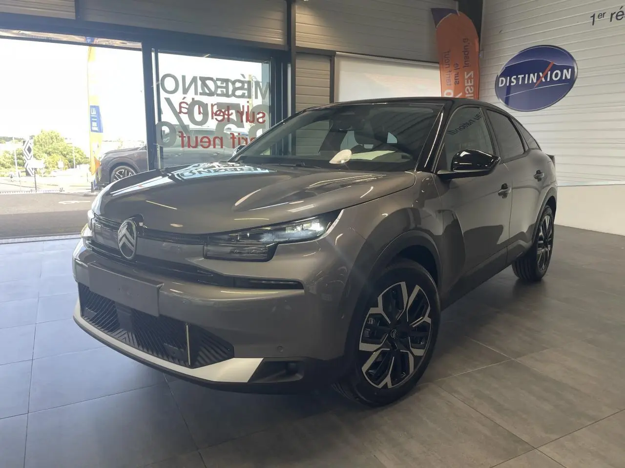 Citroën C4 gris métallisé vue 3/4 avant droit en intérieur avec toit bi-ton noir et jantes 18 pouces.