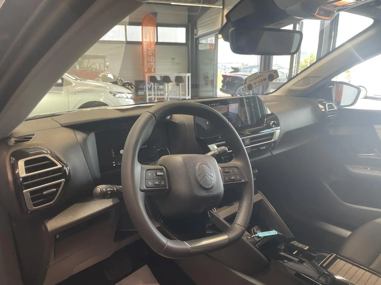 Vue intérieure côté conducteur de la Citroën C4 2026, volant cuir et tableau de bord numérique moderne.