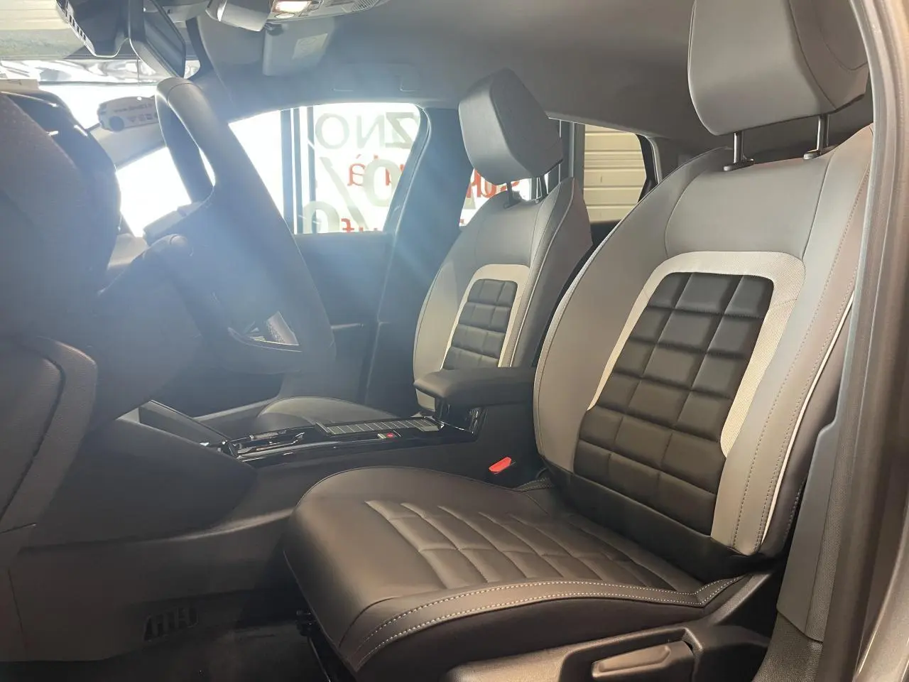 Vue intérieure côté conducteur de la Citroën C4 2026 avec sièges bi-ton gris clair et noir au design matelassé.