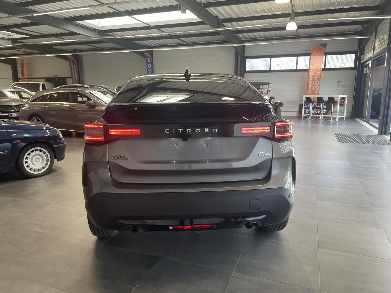 Vue arrière d'une Citroën C4 gris métallisé avec feux LED allumés dans un showroom lumineux.