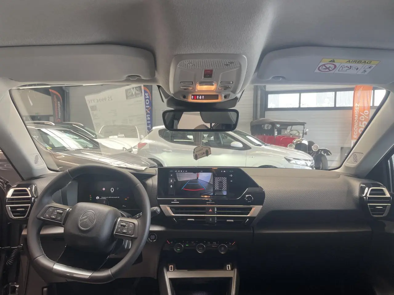 Vue intérieure avant du tableau de bord gris et noir de la Citroën C4 hybride avec écran tactile et volant multifonctions.
